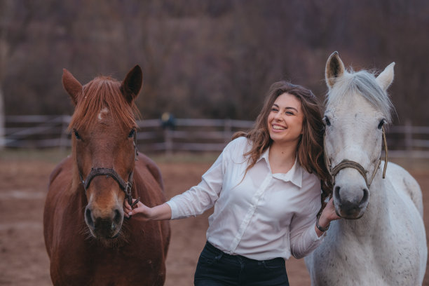 年轻女子在大自然中遛两匹马。图片下载