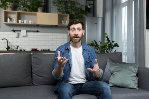 一名男子坐在家里的沙发上，全神贯注地看着网络摄像头和视频通话图片下载