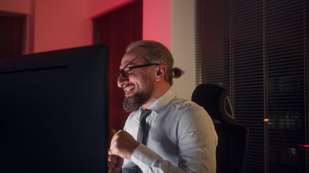 快乐英俊的中年办公室职员，西装革履，他在办公室里大笑图片下载