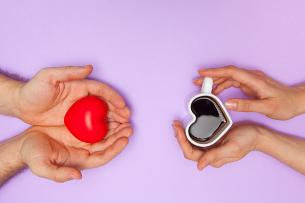 女人的手握着心形咖啡杯，男人的手握着红心杯。图片下载