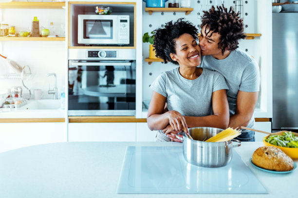 丈夫正在厨房里亲吻他的妻子。图片下载