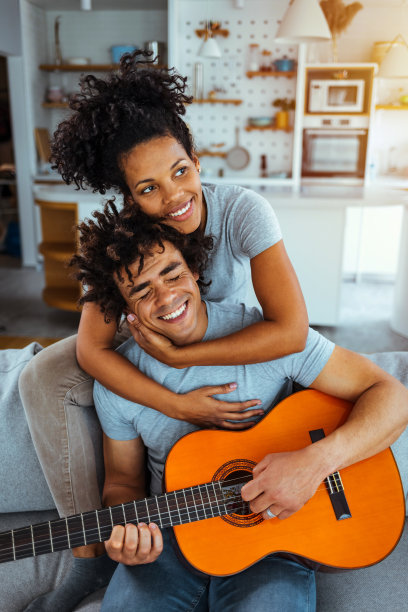 一对情侣在家里的客厅里一起弹吉他、唱歌，享受浪漫时光图片下载