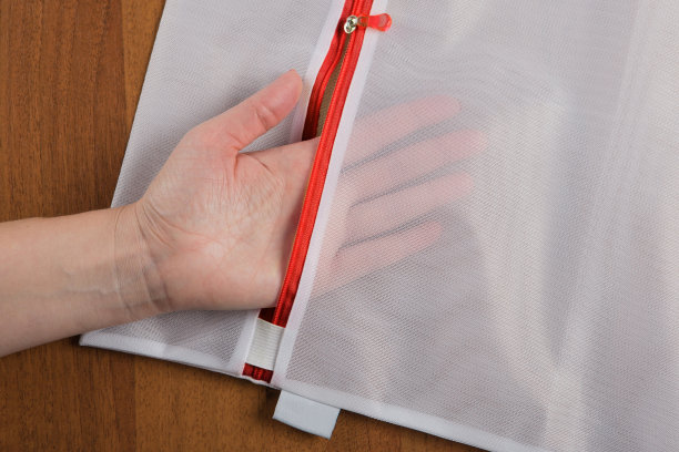 一位女性的手展示了一个白色的筛网，用来在洗衣机里洗东西图片下载