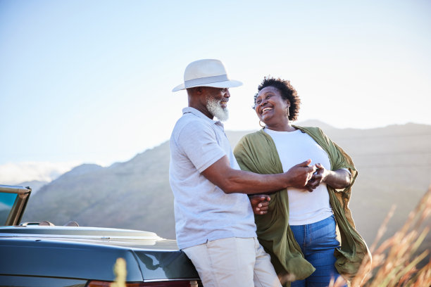 在风景优美的公路旅行中，一对成熟的夫妇一边看着照片一边大笑图片下载