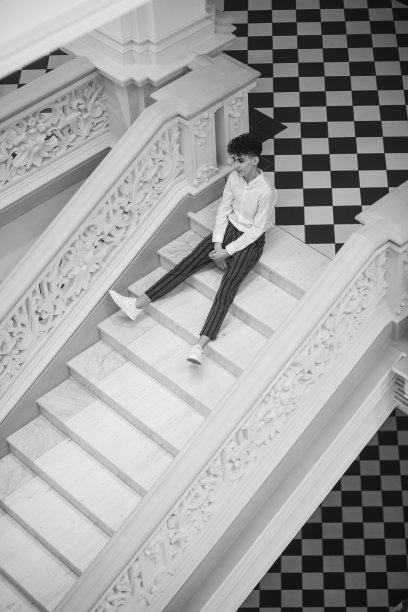 迷人的英俊青年在楼梯下摆姿势。黑白图像。图片下载