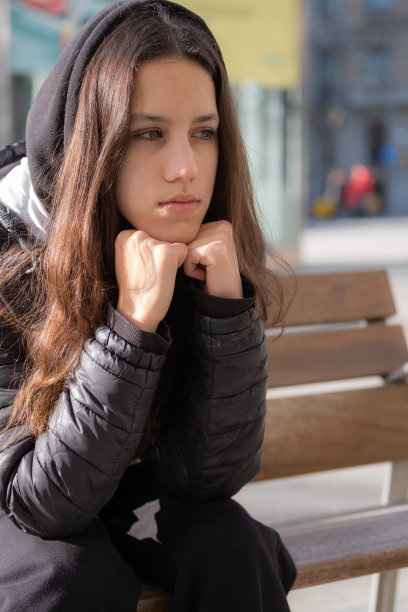 年轻女孩坐在长凳上，下巴靠在她的手女孩等待不安图片下载