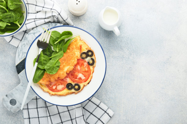 西红柿煎蛋卷，黑橄榄，白奶酪和绿色菠菜香草在灰色混凝土背景的白色盘子上。美味的早餐。健康的早餐食品。前视图。图片下载