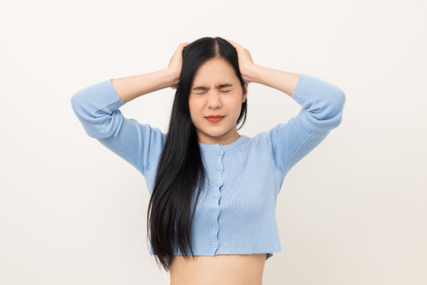 年轻的亚洲美女手摸着头，她感到压抑，压力，头痛，疲倦的工作，站在孤立的白色背景，她有症状办公室综合症。图片下载