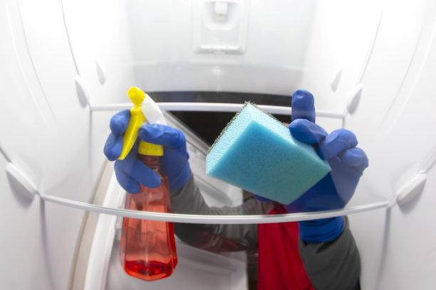 用清洁剂喷雾和海绵清洗冰箱内部。专业的食品保鲜厨房设备消毒服务图片下载