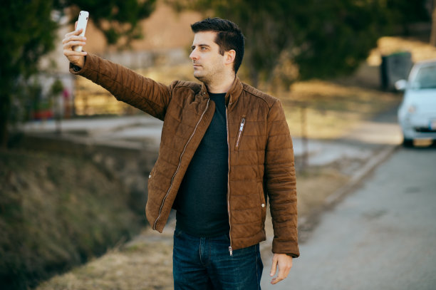 一个年轻人在用手机自拍。图片下载