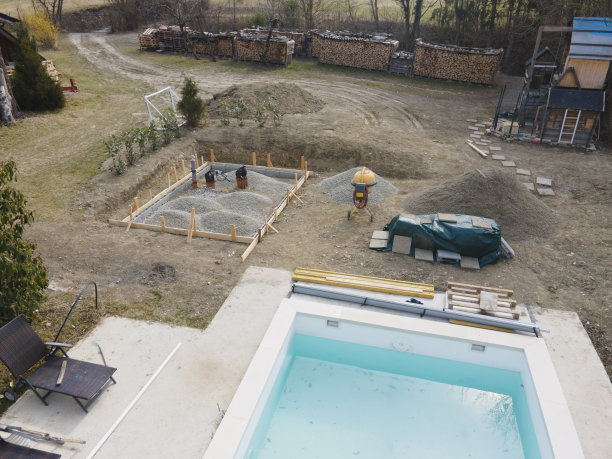 无人机拍摄的游泳池建筑工地与板材和碎石为泳池房混凝土垫块图片下载