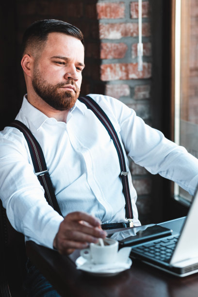 一名年轻的商人在咖啡馆里用笔记本电脑工作，桌上放着浓咖啡图片下载