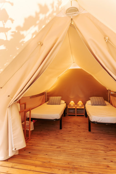 豪华帐篷，在阳光明媚的日子里，豪华而舒适的室内配有床。迷人的露营帐篷户外夏季假期和度假生活的概念素材图片