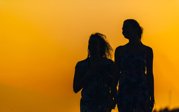 日落时分海滩上两个身材匀称的女人的剪影图片下载