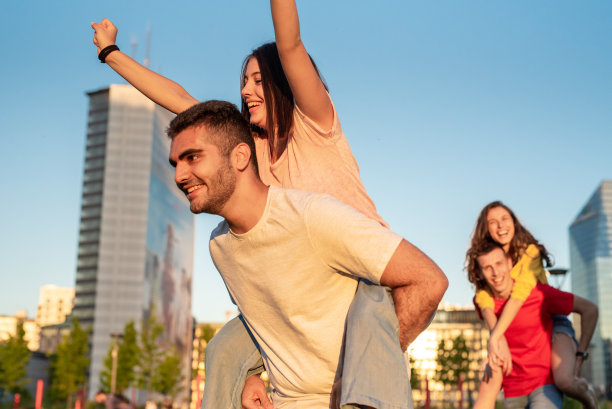 z一代人群在城市中寻欢作乐，与朋友休闲活动，两对情侣背靠背式，城市天际线背景，自由、快乐、无忧无虑的青春理念图片下载