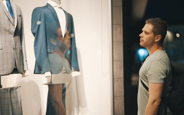 一个男人正在看服装店的橱窗。图片下载