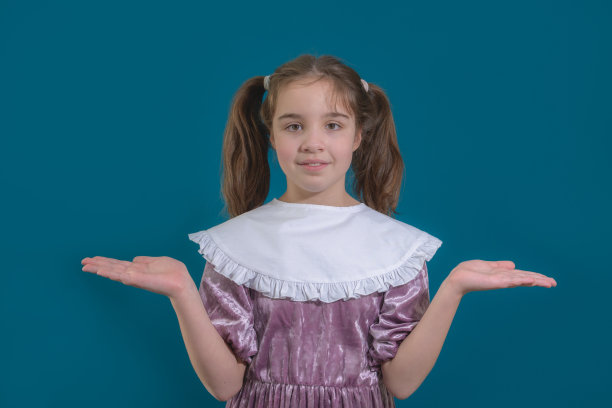 简单的是最好的。可爱的特写肖像，可爱，少女在一个简单的粉红色连衣裙与复古的衣领。孤立在蓝色背景上图片下载