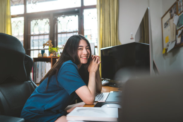 肖像快乐的微笑年轻的成年自由职业者亚洲妇女在家庭办公室与窗户的光在一天。图片下载