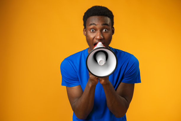 一个年轻的黑人在黄色背景下用扩音器大喊图片下载
