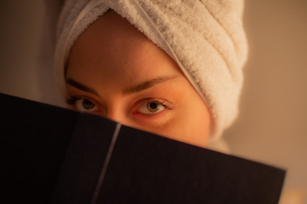 年轻美丽的女人坐在她的卧室里读一本书，她睡觉前，放松在她舒适的床上。图片下载