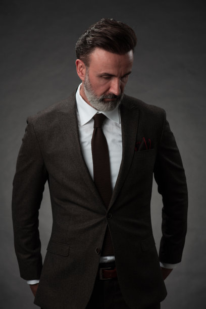 一名时尚优雅的老年商人的肖像，留着胡子和休闲的商务服装在摄影工作室孤立在黑暗的背景下手势图片下载