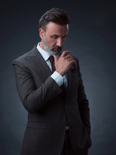 一名时尚优雅的老年商人的肖像，留着胡子和休闲的商务服装在摄影工作室孤立在黑暗的背景下手势图片下载