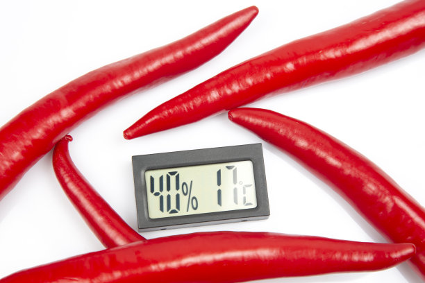 用于测量红辣椒背景上的空气温度和湿度的数字温度计。辣椒的比喻图片下载