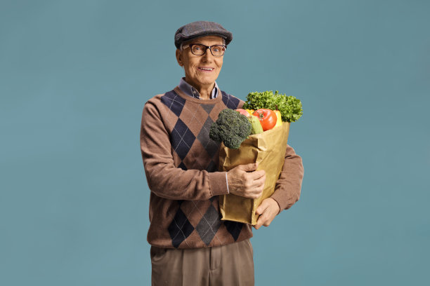 一位老人拿着一个装满杂货的纸袋图片下载