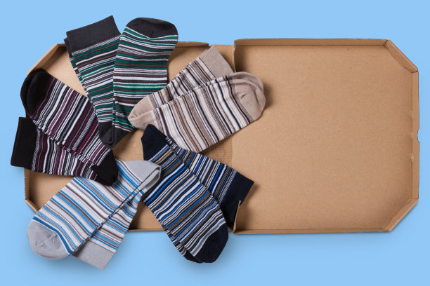 五双不同颜色的条纹袜子，放在一个盒子里围成一个圈，就像披萨，概念，在蓝色的背景上图片下载