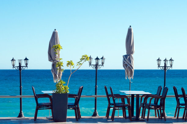 尼斯海滨的一家舒适的餐厅里，空荡荡的蓝色桌椅映衬着大海。图片下载
