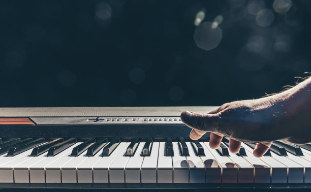 男性的手在黑暗中弹奏钢琴键。图片下载