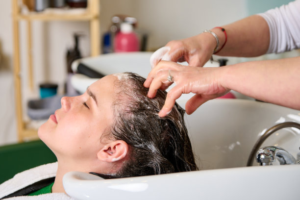 美发师在美容院用洗发水给一个黑发女孩洗头图片下载