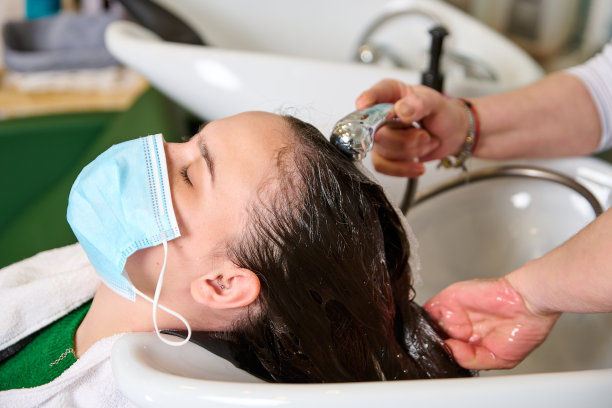 美发师在美容院用洗发水给一个黑发女孩洗头图片下载