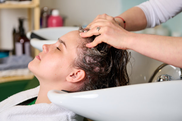 美发师在美容院用洗发水给一个黑发女孩洗头图片下载