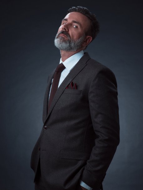 一名时尚优雅的老年商人的肖像，留着胡子和休闲的商务服装在摄影工作室孤立在黑暗的背景下手势图片下载