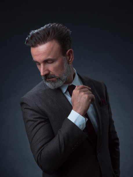 一名时尚优雅的老年商人的肖像，留着胡子和休闲的商务服装在摄影工作室孤立在黑暗的背景下手势图片下载