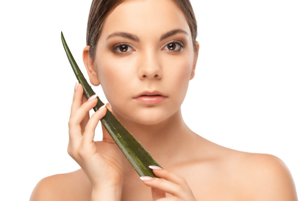 一个美丽的黑发女人的肖像与绿色芦荟叶与健康清洁的皮肤和新鲜的化妆。美学美容及化妆概念。图片下载