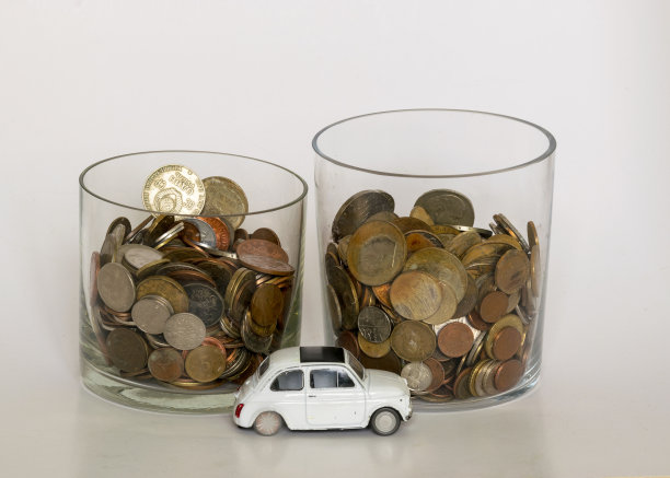 各种形状，国家和价值的旧金属硬币玻璃花瓶，在前景的玩具汽车图片下载