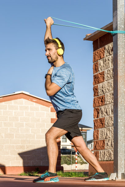 穿着蓝色t恤和黑色短裤的白人男子在户外做手部运动，测试新的松紧带图片下载