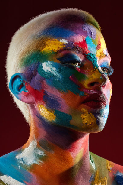 这是一名年轻女子脸上涂着彩色颜料摆姿势的画室照片图片下载