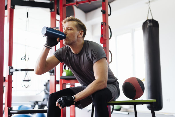 男子在健身房锻炼时喝水休息图片下载