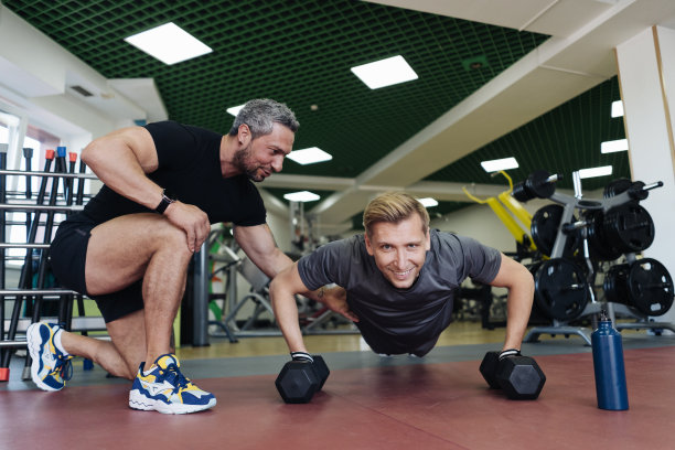 这个年轻人在健身房和私人教练一起锻炼图片下载
