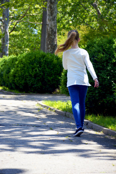 女孩沿着城市公园里铺好的小路跑步图片下载