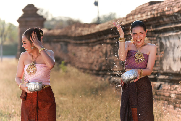 肖像欢快的年轻亚洲妇女与泰国传统服装泼洒水玩颂卡节日，泰国颂卡节日，泰国新年的文化和生活方式图片下载