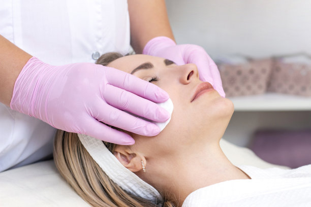 美容。近距离照片可爱的年轻女子与闭着眼睛接受面部清洁程序在美容院。图片下载