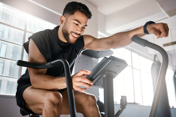 低角度拍摄的一个运动的年轻人在健身房里锻炼自行车图片下载