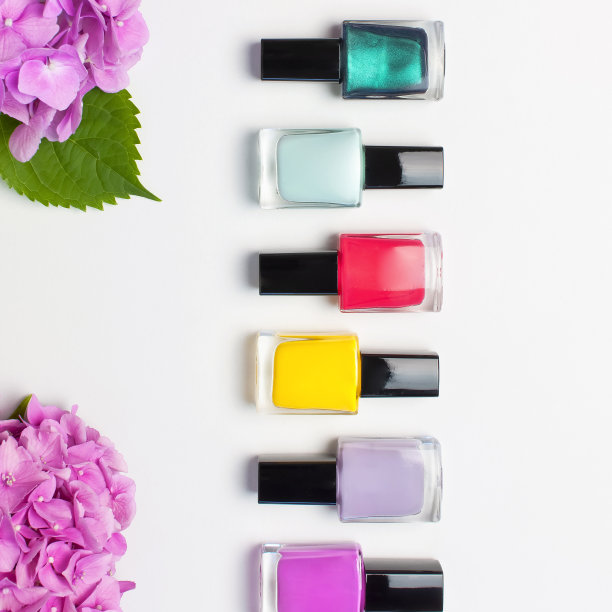 装饰化妆品，指甲油。一套不同的指甲油在光背景与粉红色绣球花顶视图平躺模拟指甲。女性化妆品。美博主的概念图片下载