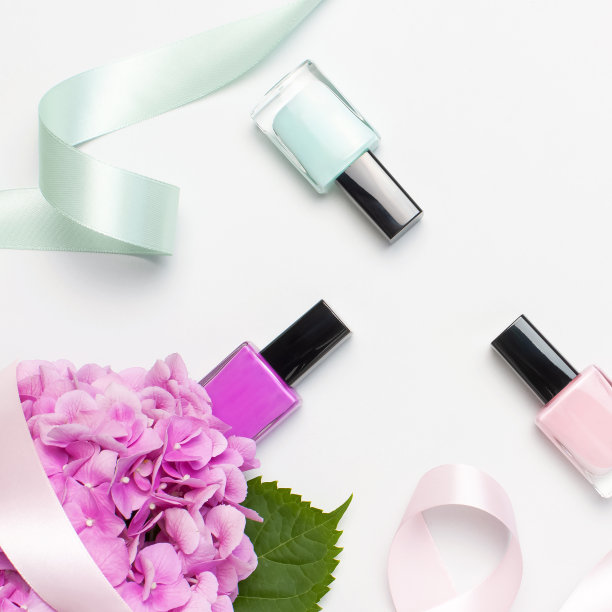 装饰化妆品，指甲油。一套不同的指甲油在光背景与粉红色绣球花顶视图平躺模拟指甲。女性化妆品。美博主的概念图片下载