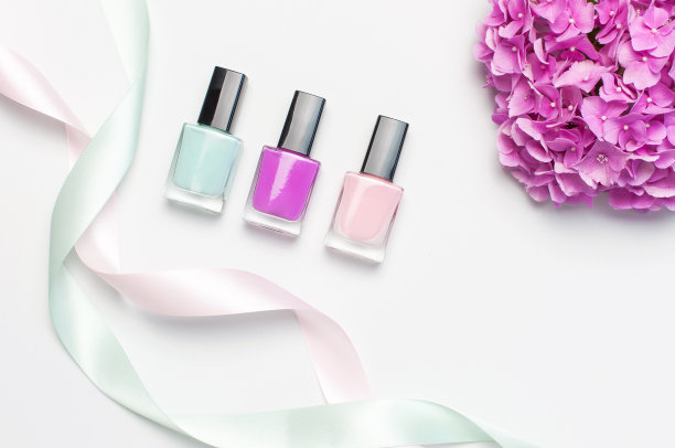 装饰化妆品，指甲油。一套不同的指甲油在光背景与粉红色绣球花顶视图平躺模拟指甲。女性化妆品。美博主的概念图片下载