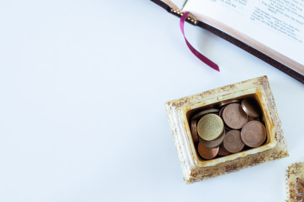 硬币在一个金色的盒子与打开的白色背景的圣经书图片下载